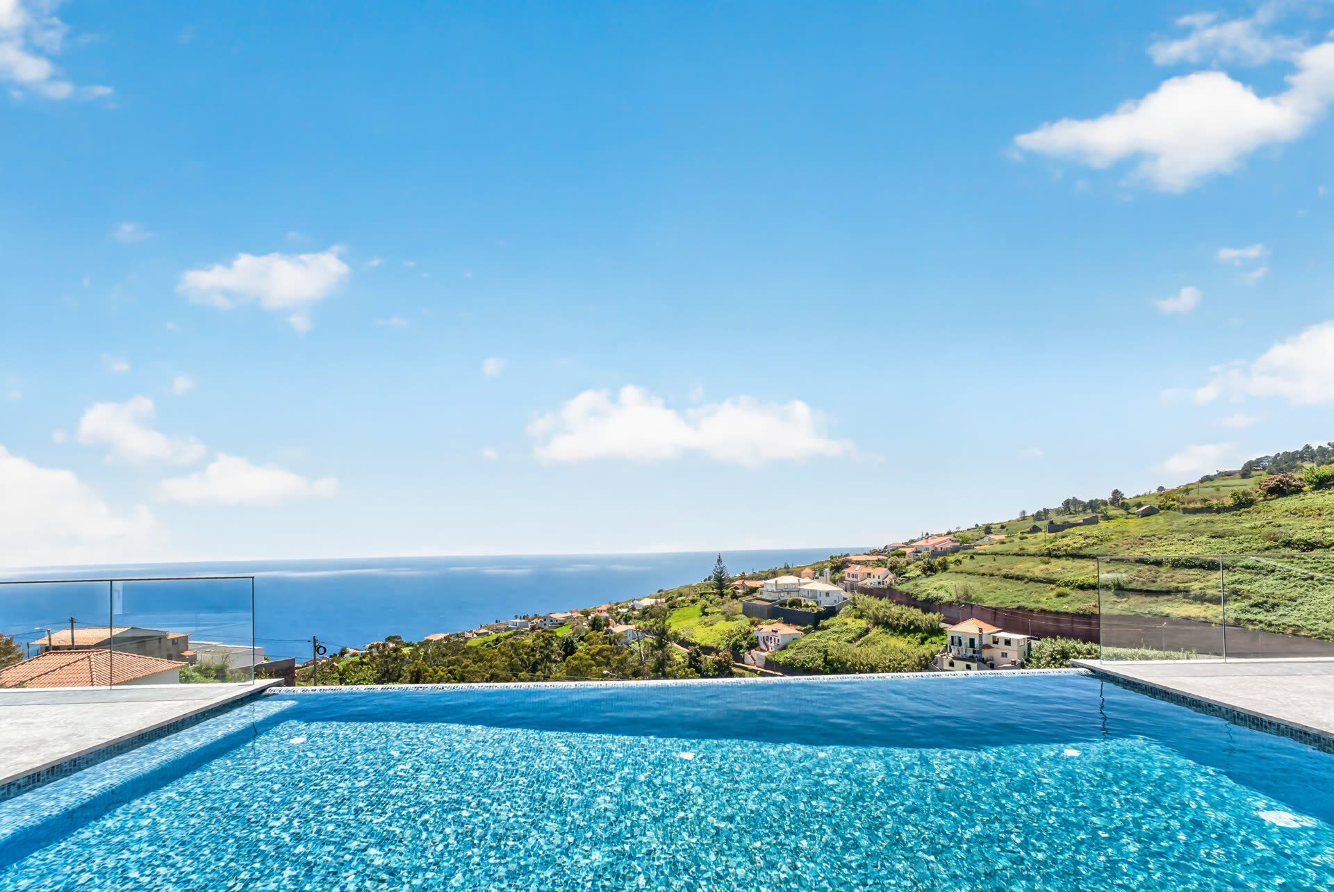 Piscina infinita sobre as encostas verdes da Madeira, com o mar ao fundo